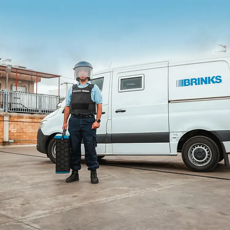 Φύλακας της Brink's Cyprus με ασφαλισμένη κασέτα μπροστά από θωρακισμένο όχημα